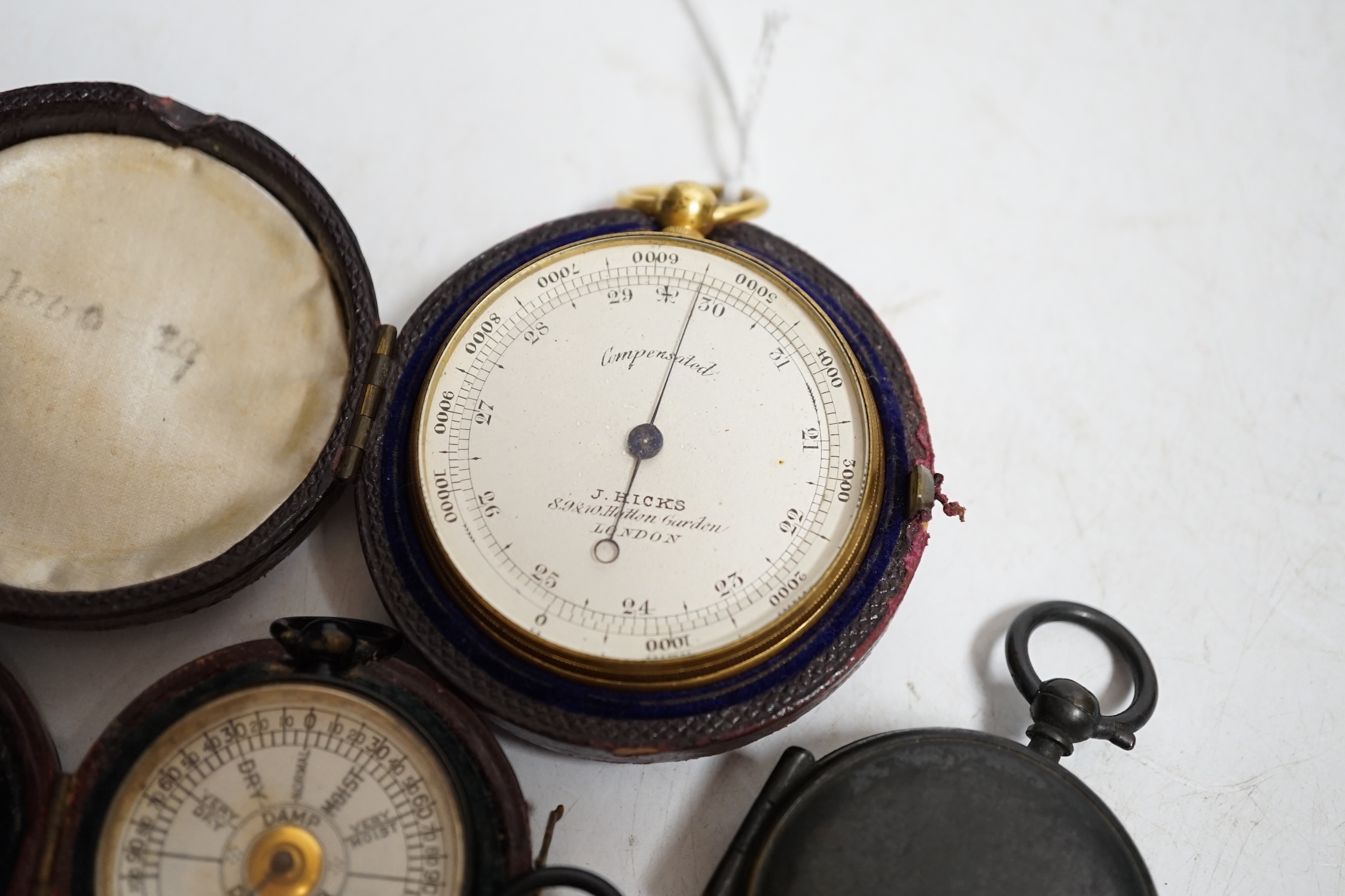 Two pocket damp detectors, a pocket barometer, and a compass, three with original leather cases. Condition - fair